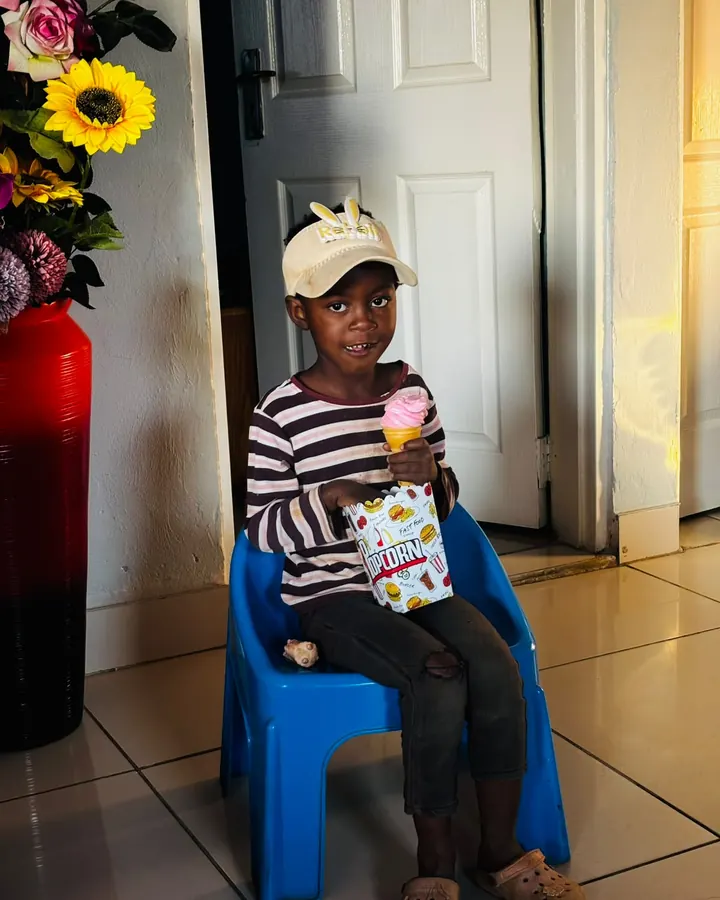 A boy with a strawberry soft-serve and a box of popcorn
