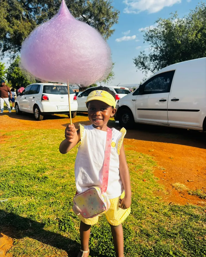 A girl holding an enormous pink candy floss at an outdoor event